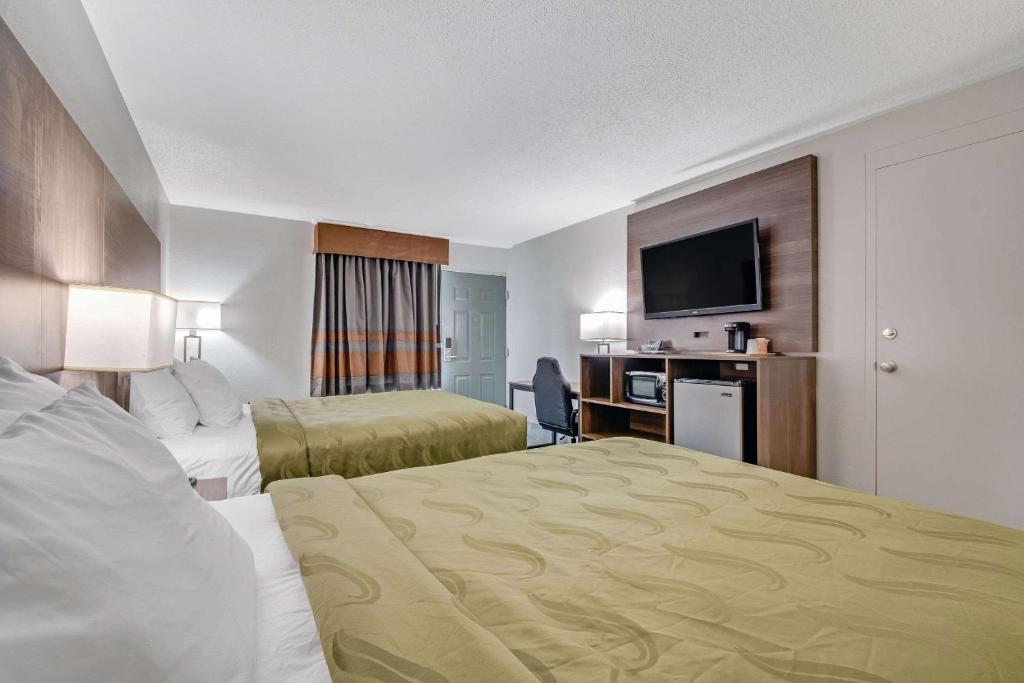 a hotel room with two beds and a flat screen tv at Quality Inn in Dalton