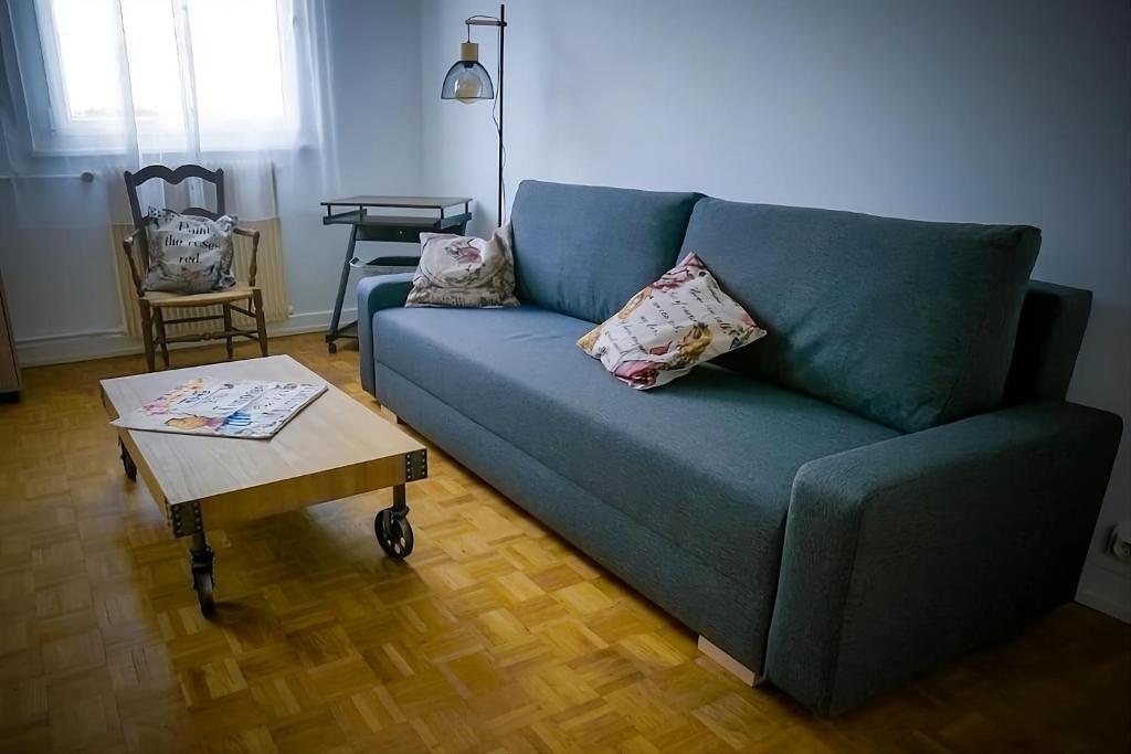 un salon avec un canapé bleu et une table basse dans l'établissement wonderland appart tout équipé, à Strasbourg