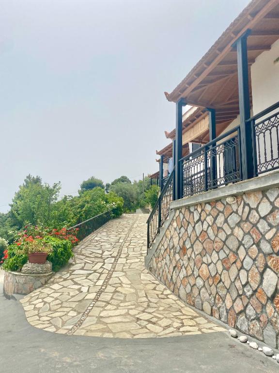 a stone walkway in front of a building with flowers at Betsanis Stafylos Apartments in Stafylos