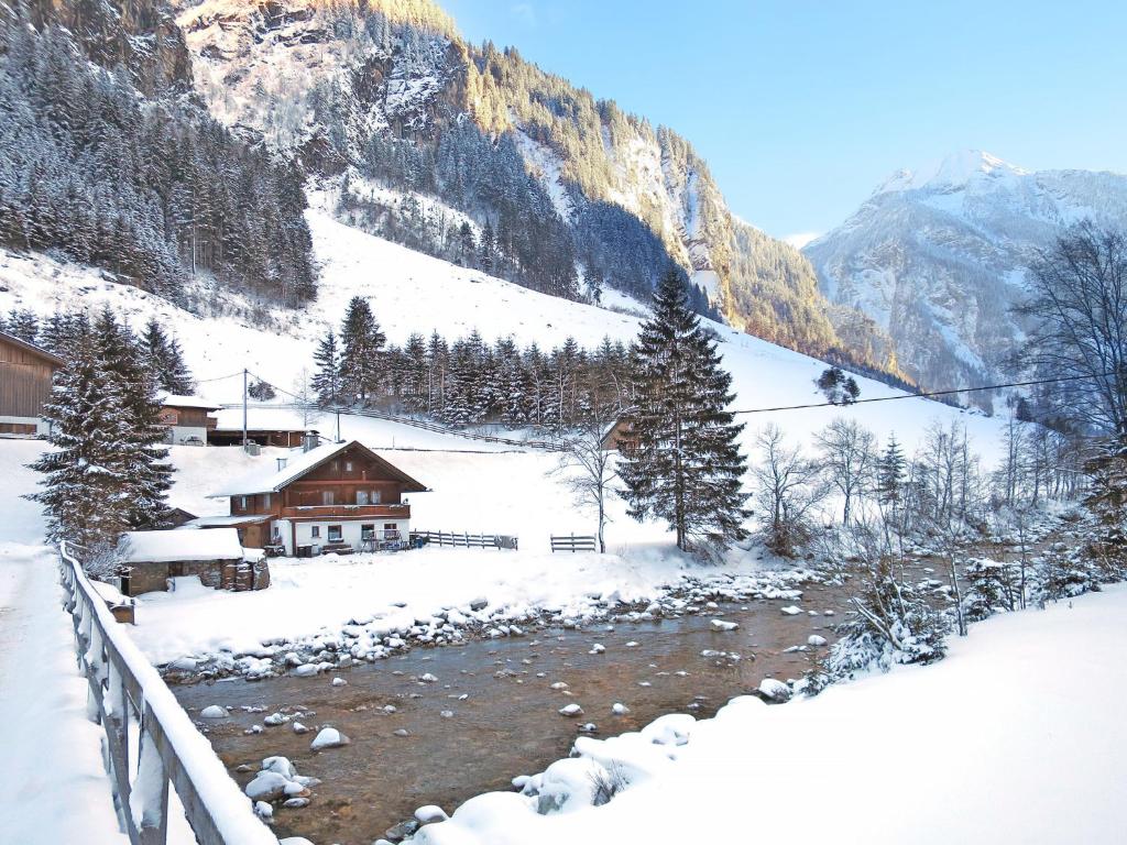 a snow covered mountain with a house and a river at Holiday Home Farm Eben by Interhome in Ginzling