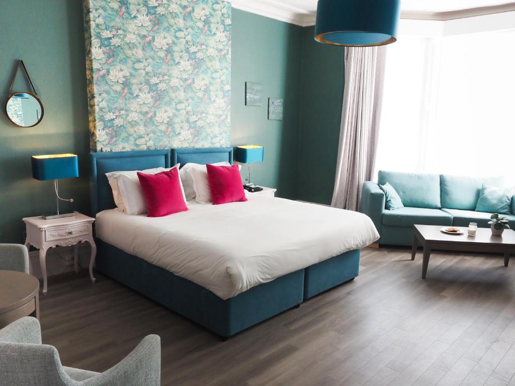 sypialnia z łóżkiem z czerwonymi poduszkami i kanapą w obiekcie Hotel Collingwood BW Signature Collection w Bournemouth