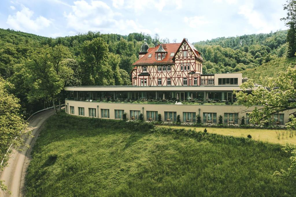 une grande maison au sommet d'une colline herbeuse dans l'établissement Hotel & Spa Suiten FreiWerk, à Stolberg