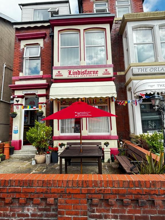 a red umbrella sitting in front of a building at Lindisfarne Holiday Apartments - Families & Couples Only in Blackpool