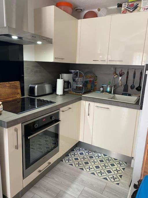 une cuisine avec des armoires blanches et un four à plaques de cuisson dans l'établissement Le central, avec terrasse et parking saint raphael, à Saint-Raphaël