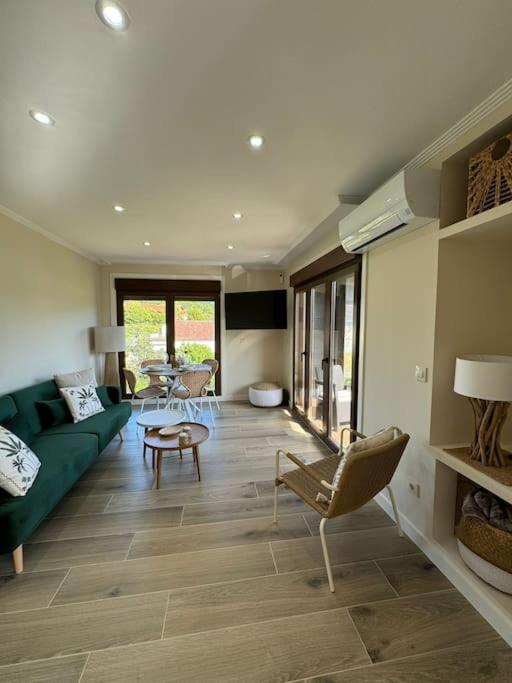 a living room with a green couch and chairs at Vivienda junto a la playa de Loira in Seixo