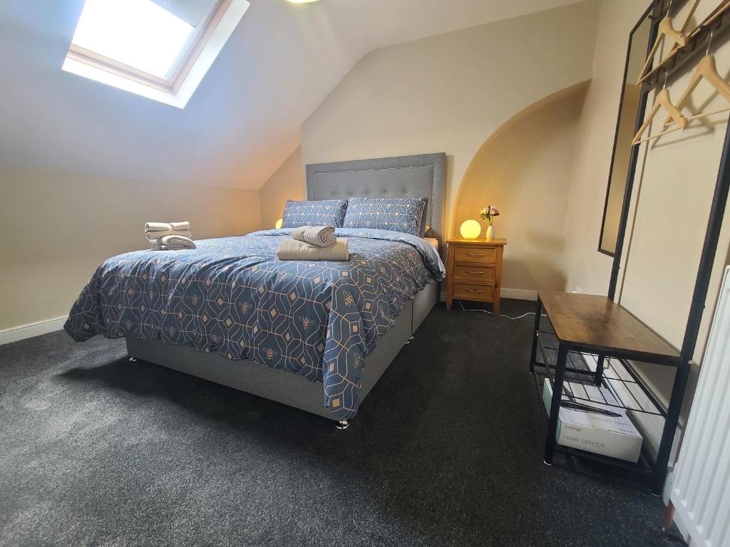 a bedroom with a bed with a blue comforter and a table at Roskeen Townhouse in Belfast