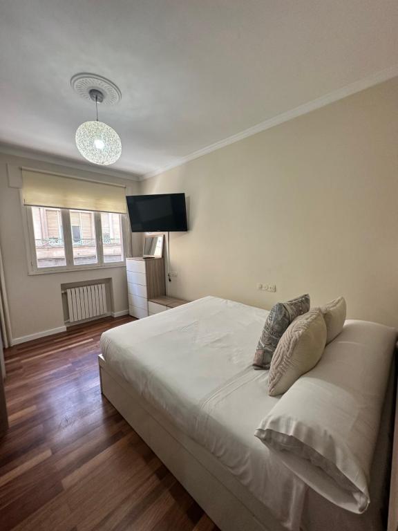 ein Schlafzimmer mit einem großen weißen Bett und einem Flachbildfernseher in der Unterkunft Alojamiento en el corazón de Monforte de Lemos en Ribeira Sacra in Monforte de Lemos