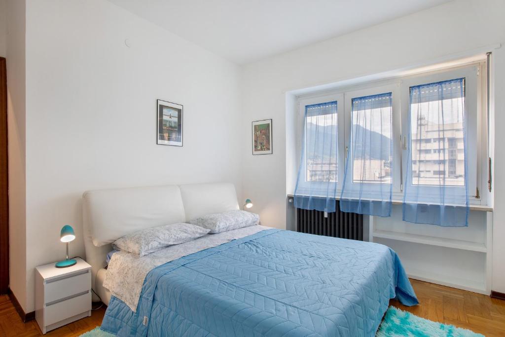 a bedroom with a blue bed and two windows at Casa Rosa Aosta in Aosta