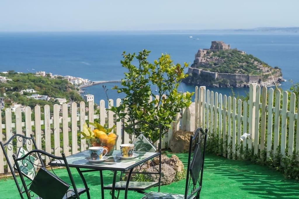 a table and chairs with a view of an island at La Finestra sul Castello in Ischia