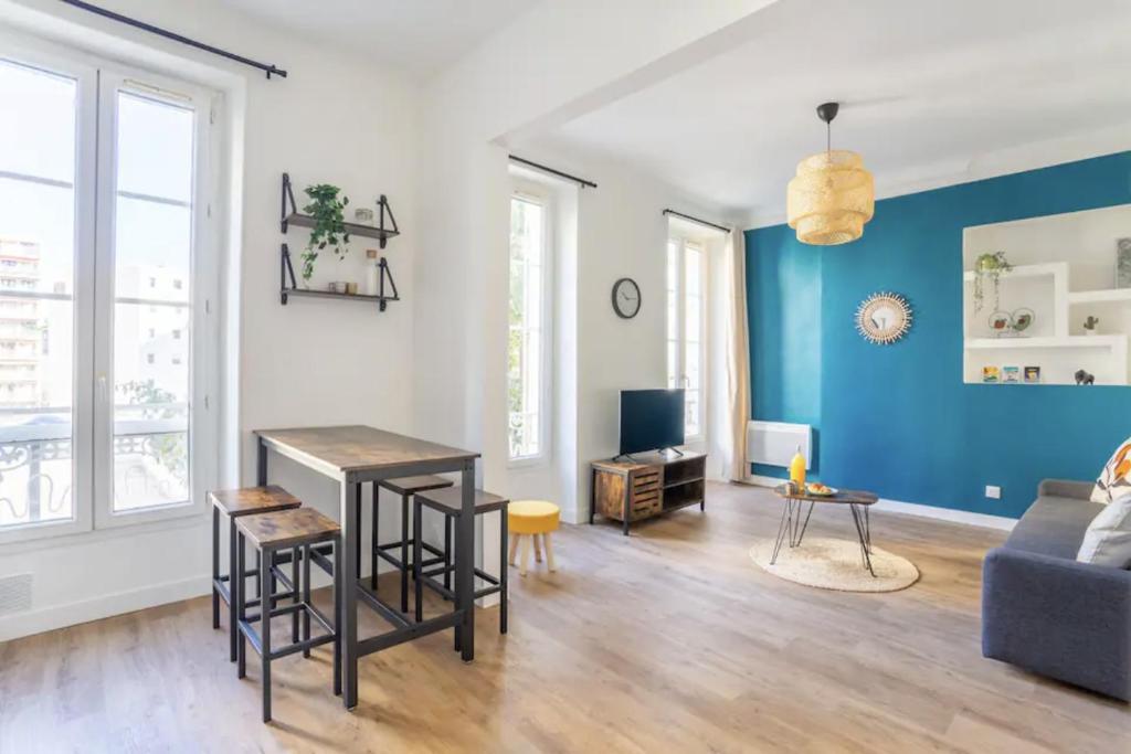 un salon avec une table et un mur bleu dans l'établissement Jolie appartement proche de la joliette 14LAN, à Marseille