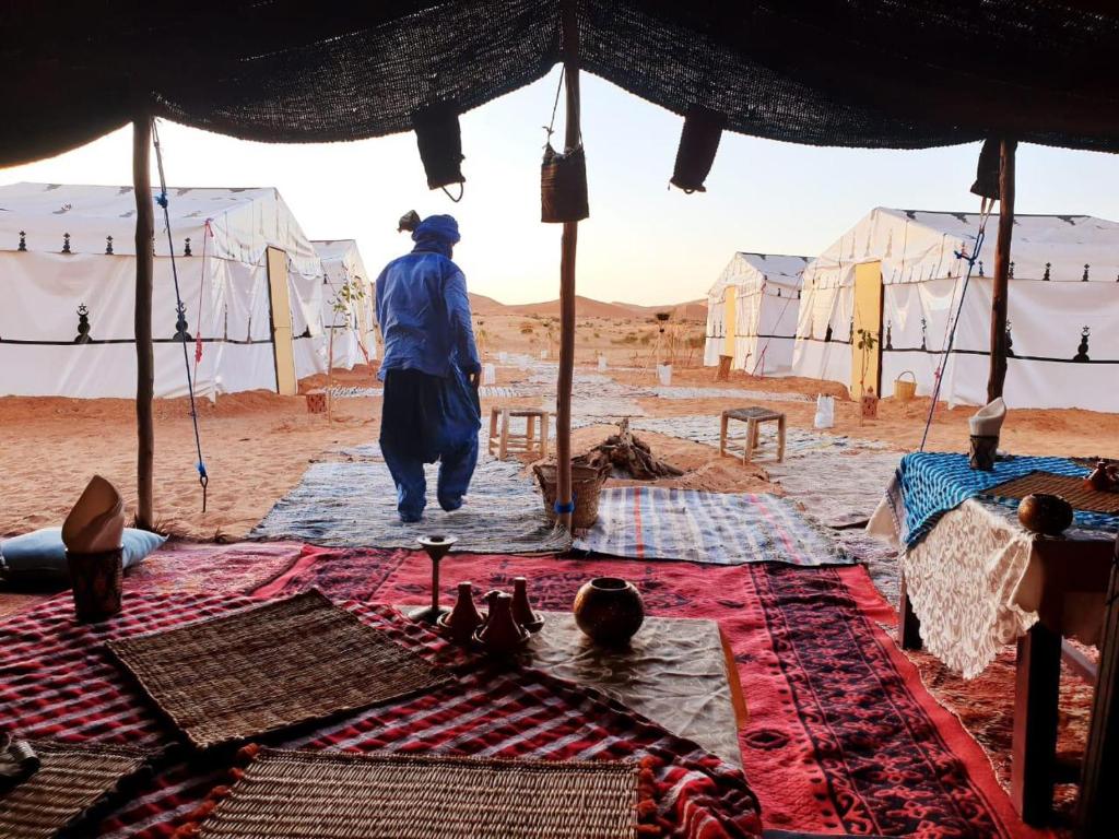 a man walking through a tent in the desert at Tuareg Luxury Camp in Merzouga