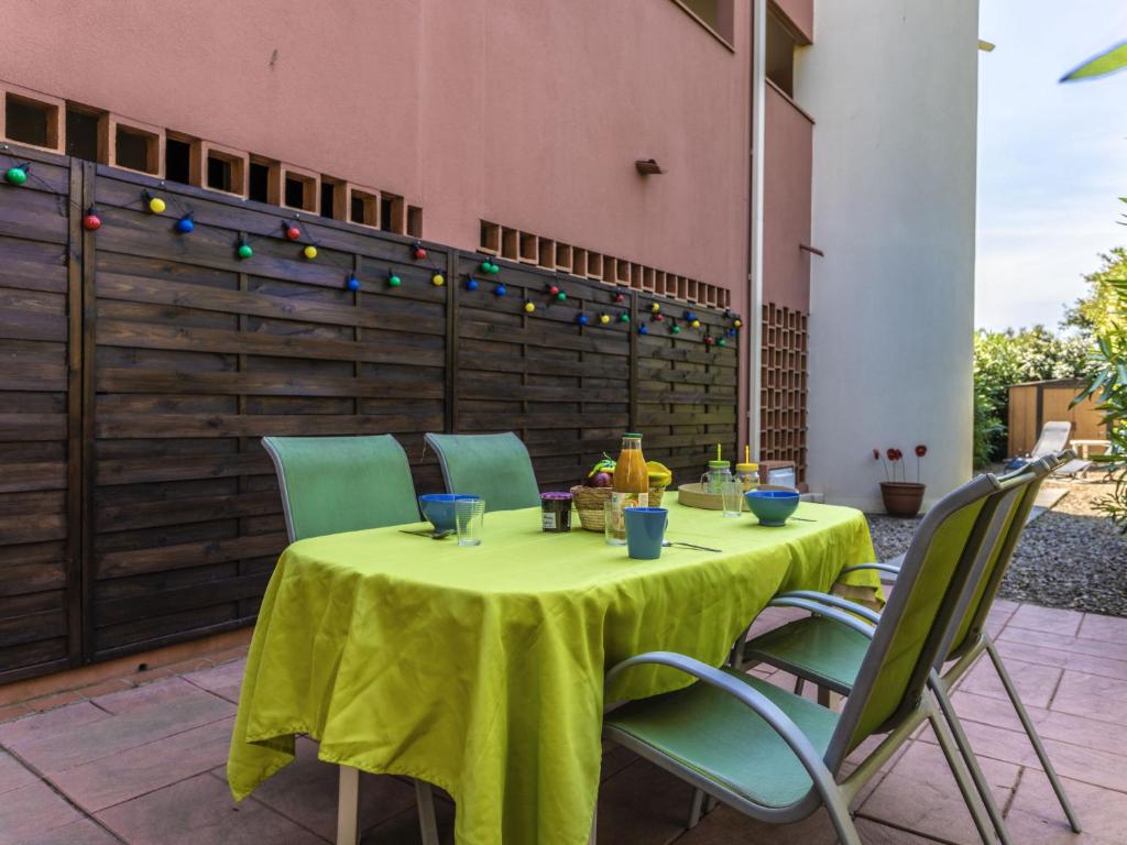 une table avec un tissu de table jaune sur une terrasse dans l'établissement Studio Club Du Golf by Interhome, au Cap d'Agde