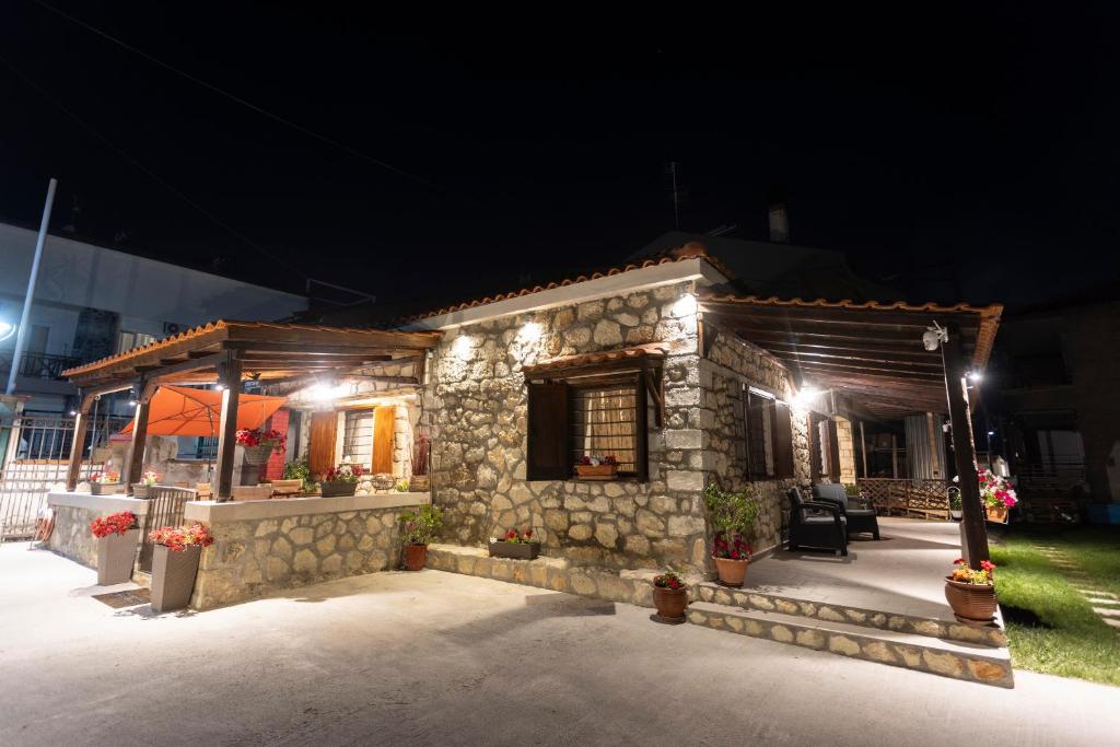 a stone house with a patio at night at Stone House Dimitra in Polykhrono