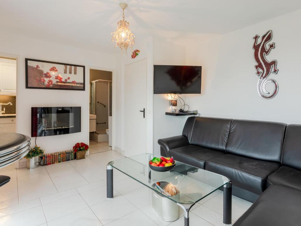 un salon avec un canapé noir et une table dans l'établissement Studio Les flots bleu by Interhome, à Trouville-sur-Mer