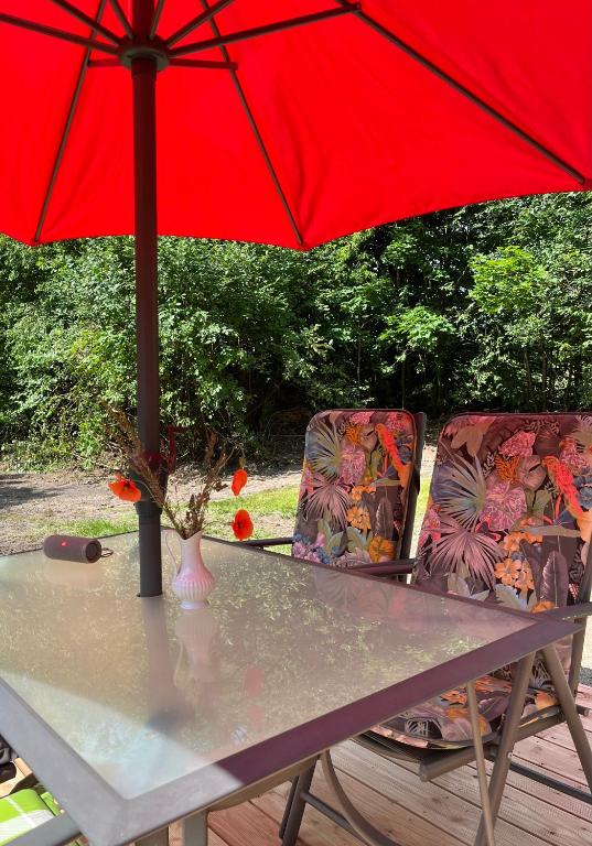 a table with a red umbrella and two chairs at Haus Kanalliebe in Nübbel