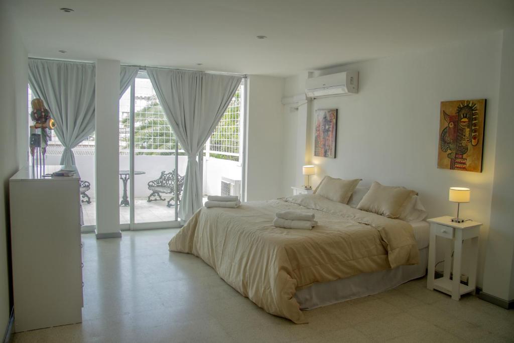 a white bedroom with a large bed and a balcony at Tacha in Buenos Aires