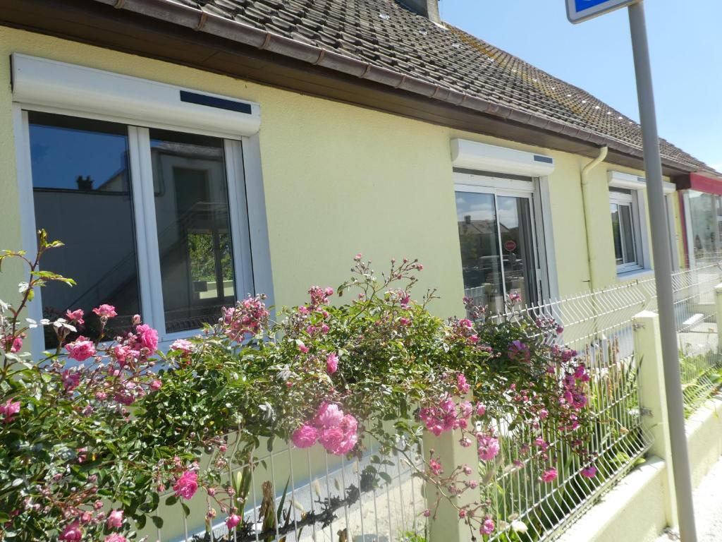 une maison avec des fleurs roses sur le balcon dans l'établissement Maison - 150m plage- 4 personnes - Asnelles, à Asnelles