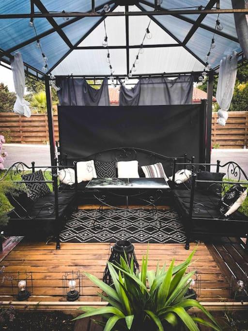 un patio avec un canapé noir sous un parasol dans l'établissement Belle appartement T2 avec jardin, à Labenne
