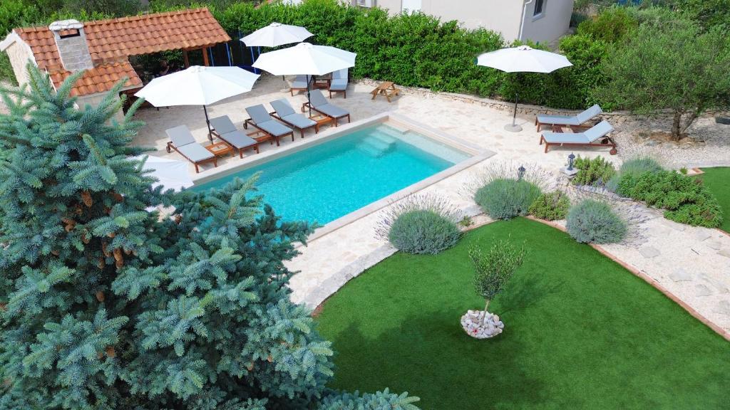 an overhead view of a swimming pool with chairs and umbrellas at Laura Apartments in Brodarica