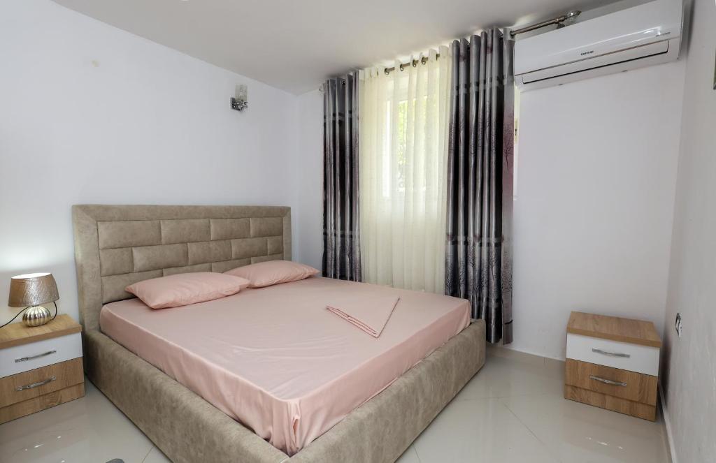 1 dormitorio con cama con sábanas rosas y ventana en Guesthouse Berati, en Berat