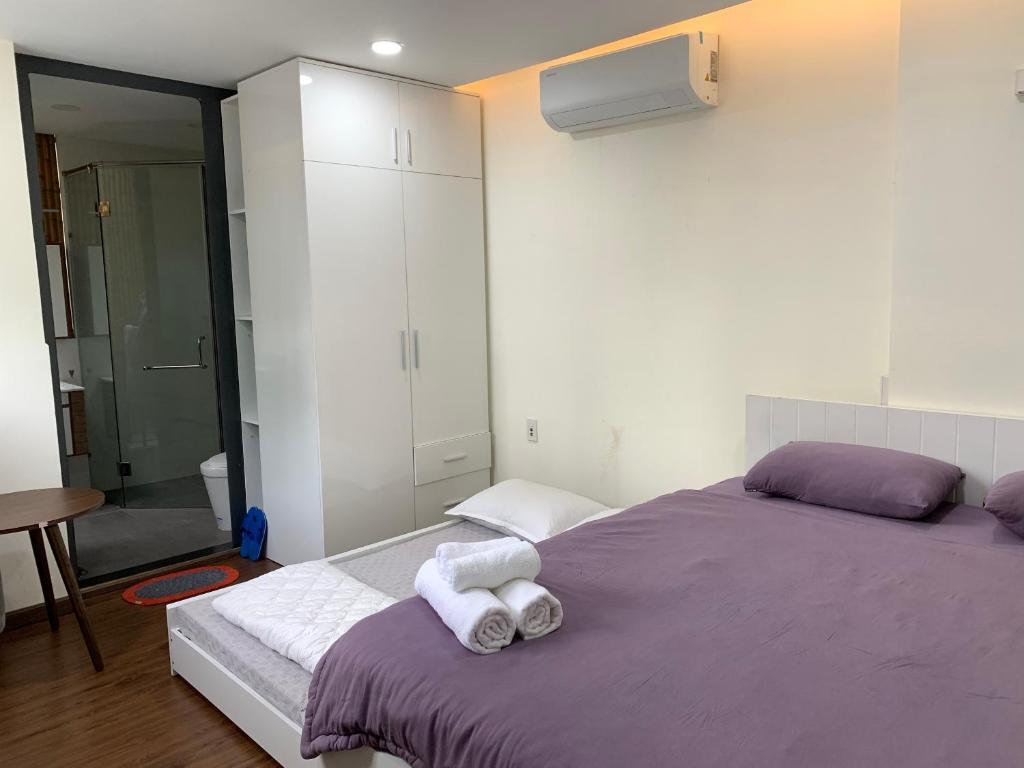 胡志明市的住宿－LUCY HOTEL & APARTMENT，一间卧室配有一张紫色床和毛巾