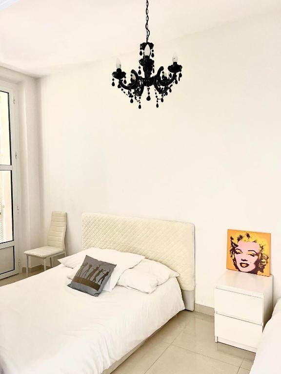 - une chambre blanche avec un lit et un lustre dans l'établissement Cannes plage 2 pièces Croisette centre ville, à Cannes