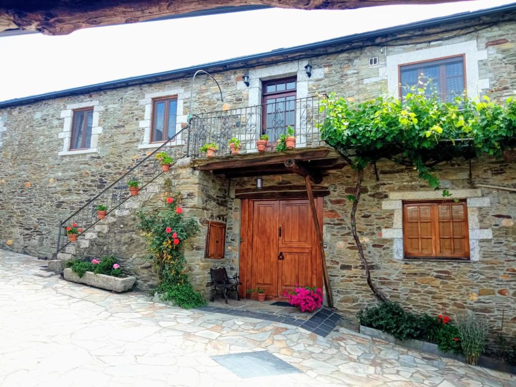 an old stone house with a wooden door and a balcony at O Val de Vilaboa in Bóveda