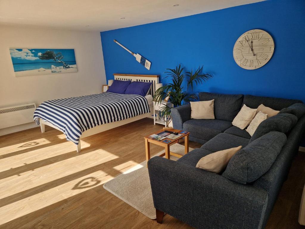 a living room with a couch and a clock on the wall at Nautical themed Guest House with private patio on the outskirts of Lymington in Lymington