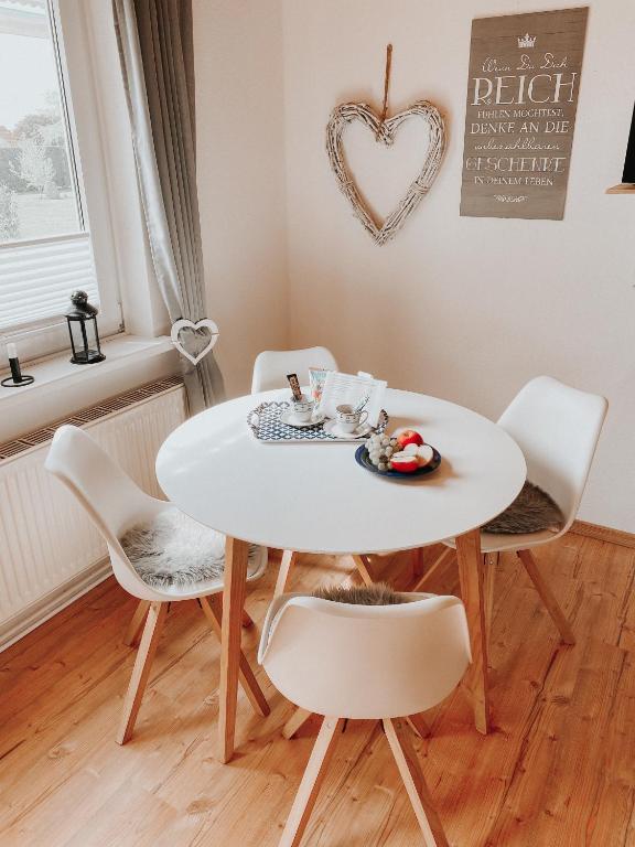 a white table and chairs in a room with a heart sign at Ferienwohnung Nr 6 in Hinrichsdorf