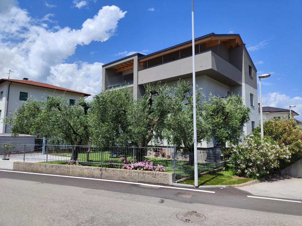 un edificio bianco con alberi di fronte a una strada di Oasi degli Ulivi a Riva del Garda