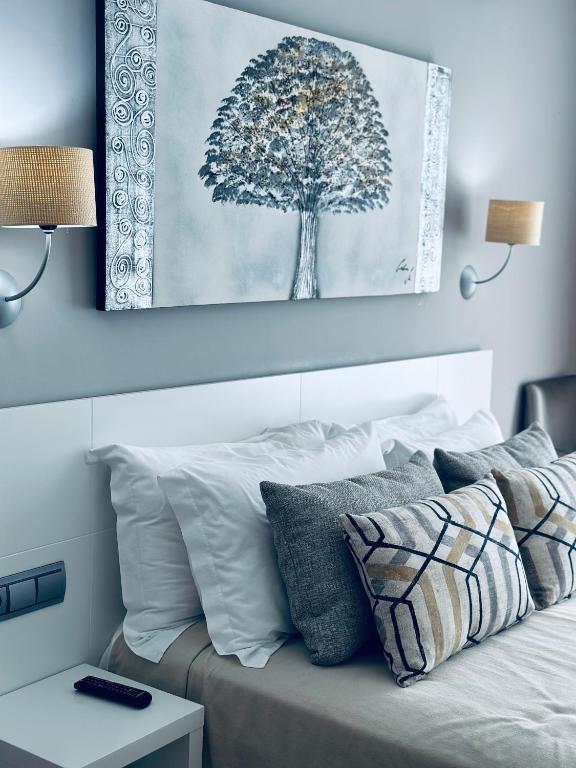 a bedroom with a bed with a tree painting on the wall at Hotel Las Olas in Noja