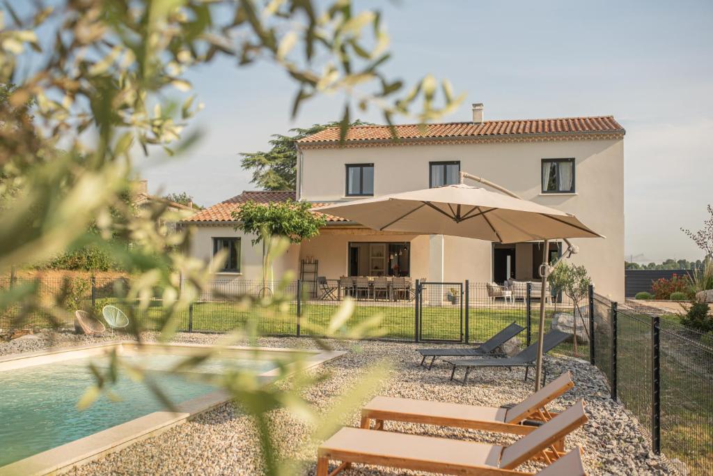 a house with a pool and an umbrella at Les Villas Chamontines - La Villa des Chênes in Labeaume