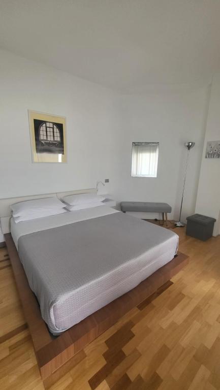 uma grande cama branca num quarto com piso em madeira em San Siro Terrace Attic Apartment Milano em Milão