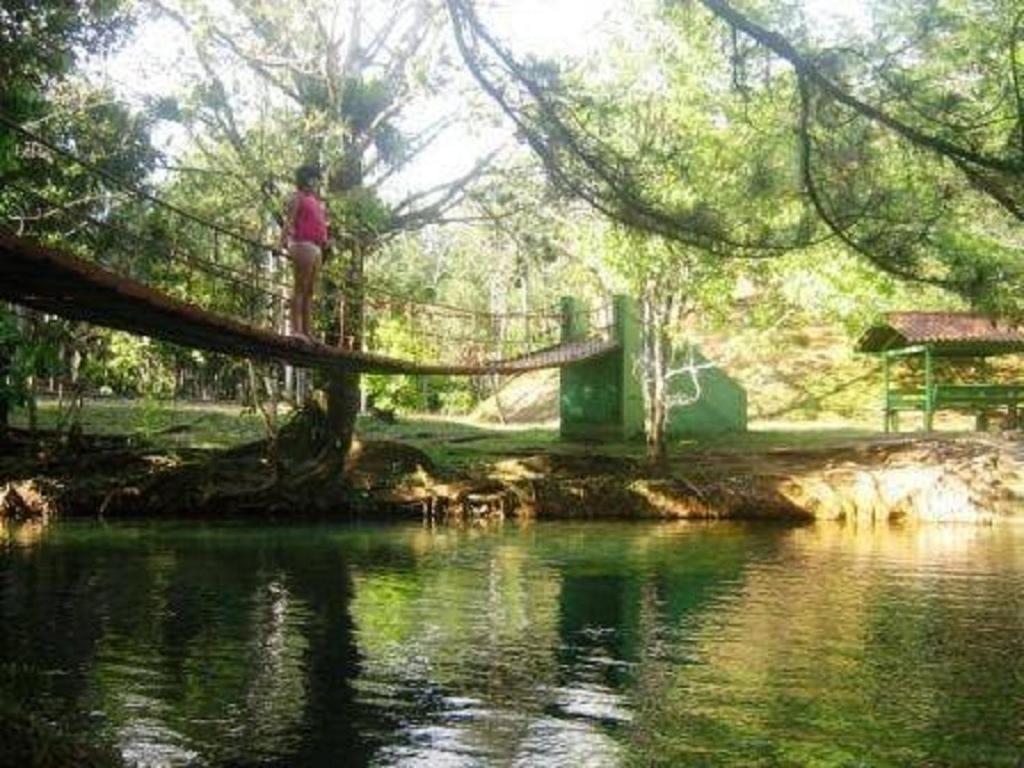 una persona parada en un puente colgante sobre un río en Casa Grande Retiro para grupos en Cerro Azul