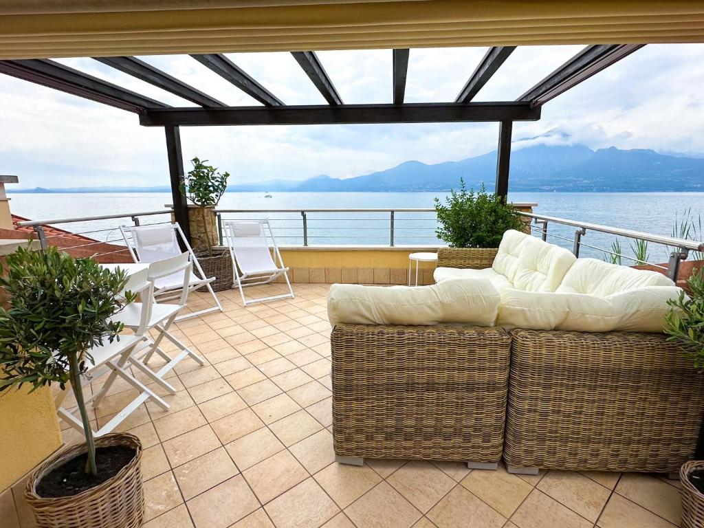 a patio with a couch and a table and chairs at ApartmentsGarda - Il Tesoro del Lago in Torri del Benaco