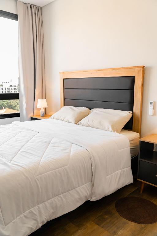 Un dormitorio con una gran cama blanca y una ventana. en Excelente Depto en Las Lomas, en Asunción