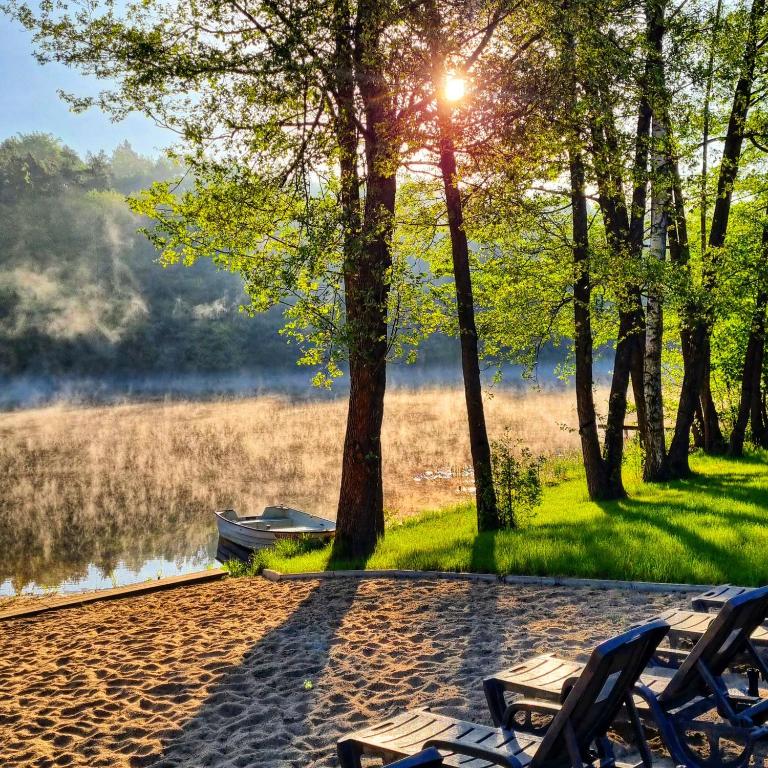 a group of chairs sitting next to a lake at Mazurska Zatoka Resort & Spa - Apartamenty nad jeziorem z prywatną plażą i podgrzewanym basenem zewnętrznym, Mazury w rytmie SLOW in Łukta
