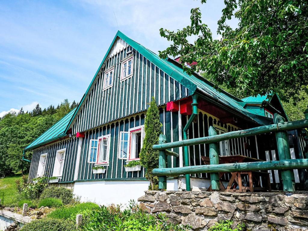 a green and white house with a stone wall at Holiday Home U Myšáka by Interhome in Tanvald