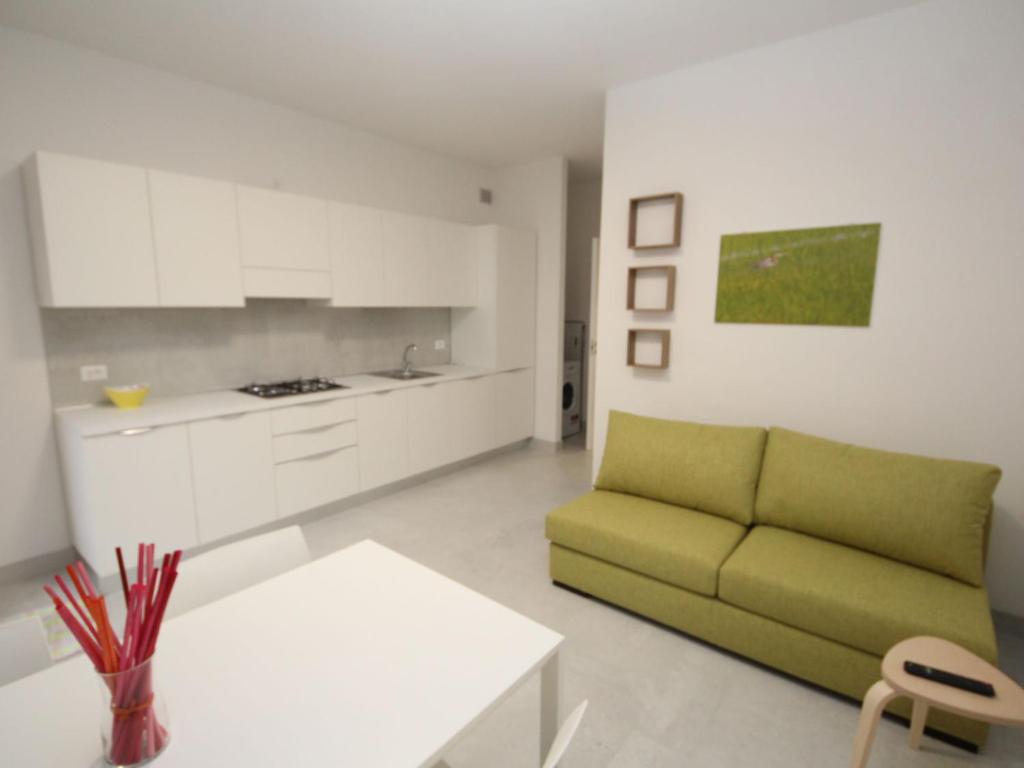 a living room with a green couch and a kitchen at Apartment Marcello-7 by Interhome in Rosolina Mare