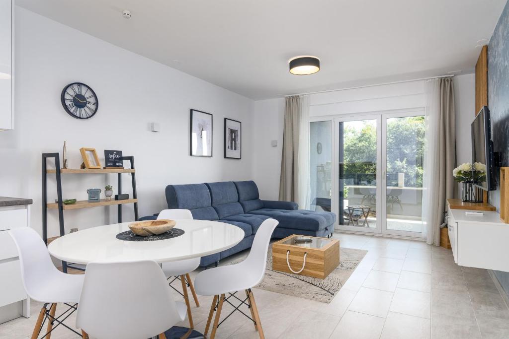 Una sala de estar con un sofá azul y una mesa y sillas. en Relax Trogir, en Trogir
