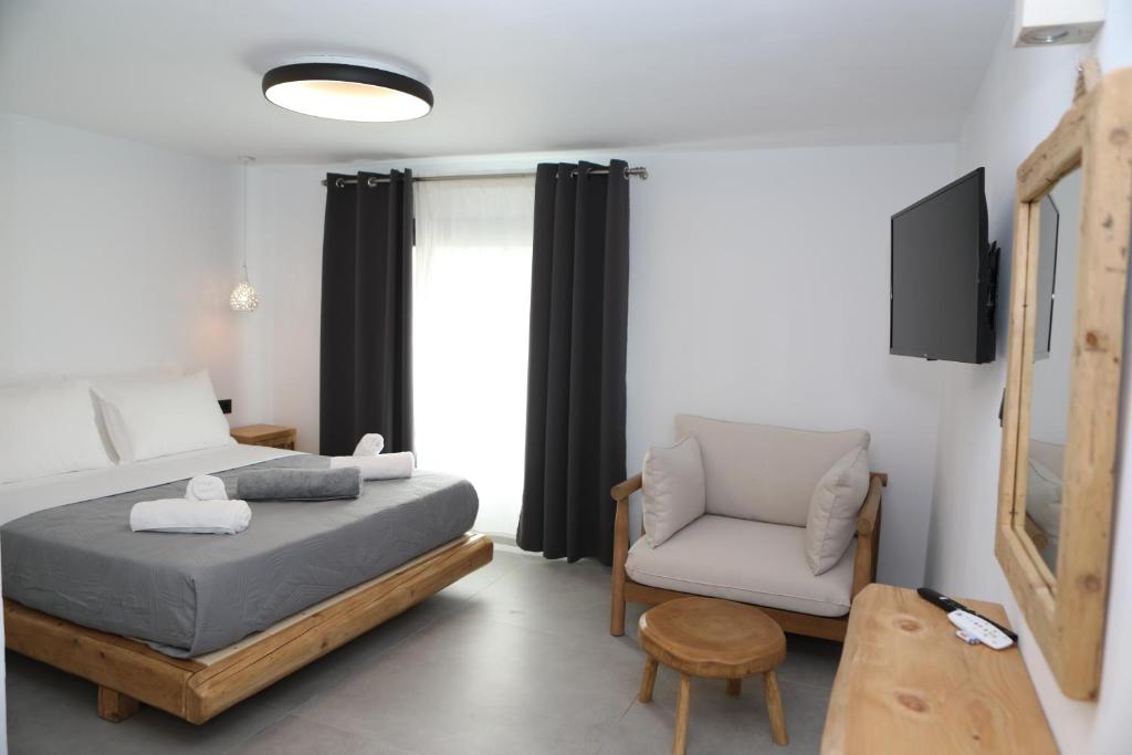 a small bedroom with a bed and a chair at White Dream Suites Antiparos in Antiparos
