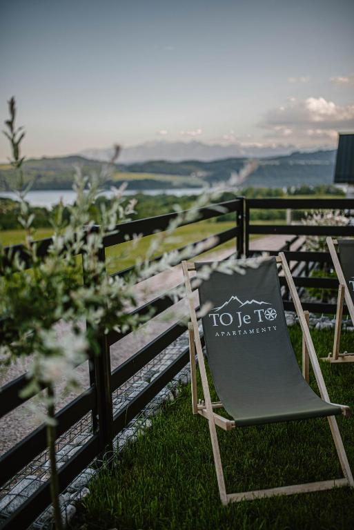 a chair sitting in the grass next to a fence at To Je To apartamenty in Maniowy