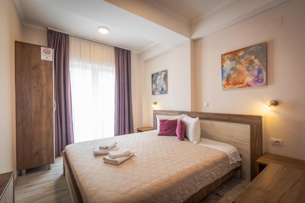 a bedroom with a large bed with pink pillows at Boulevard Apartments in Gevgelija