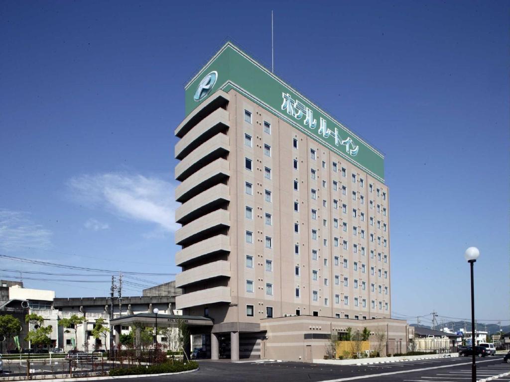 a large hotel building with a green sign on it at Hotel Route-Inn Hamanako in Kosai