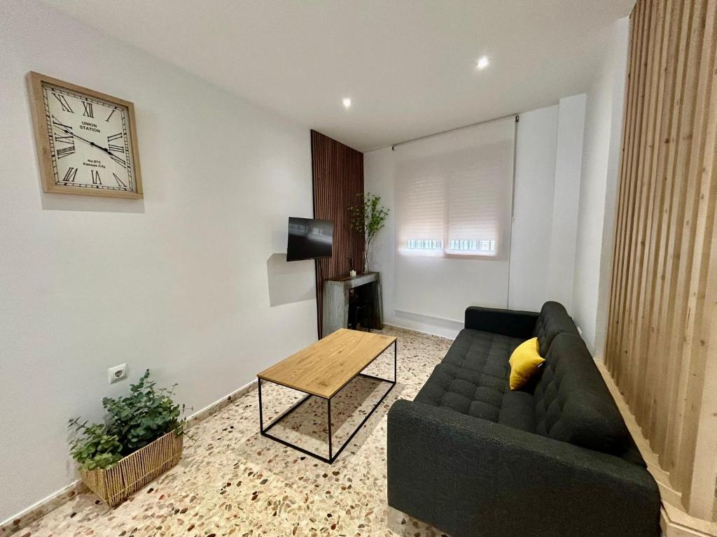 ein Wohnzimmer mit einer Couch und einer Uhr an der Wand in der Unterkunft Casa Mariquilla in Sanlúcar de Barrameda