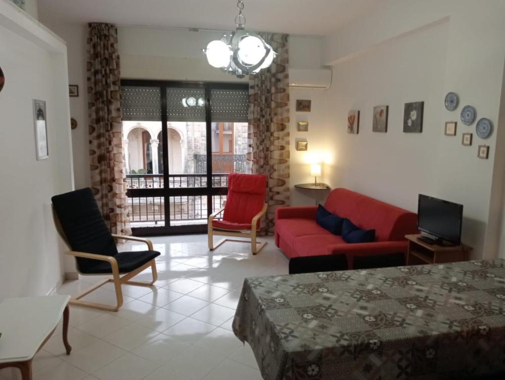 un salon avec un canapé rouge et des chaises dans l'établissement casa del corso, à Canicattini Bagni