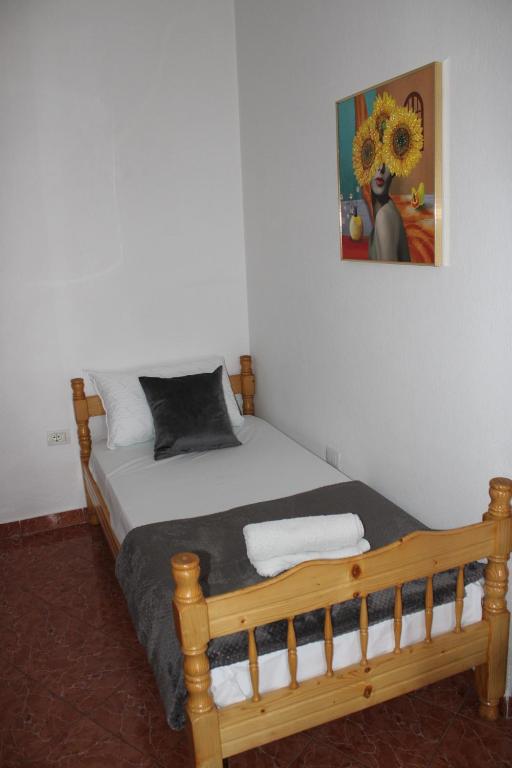 a bedroom with a wooden bed with a painting on the wall at Crew Hostel Tirana in Tirana