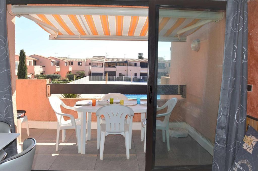 un patio avec une table et des chaises sur un balcon dans l'établissement Appart 2 pièces 4 couchages PORT LEUCATE NATURISME PL010-830, à Port-Leucate