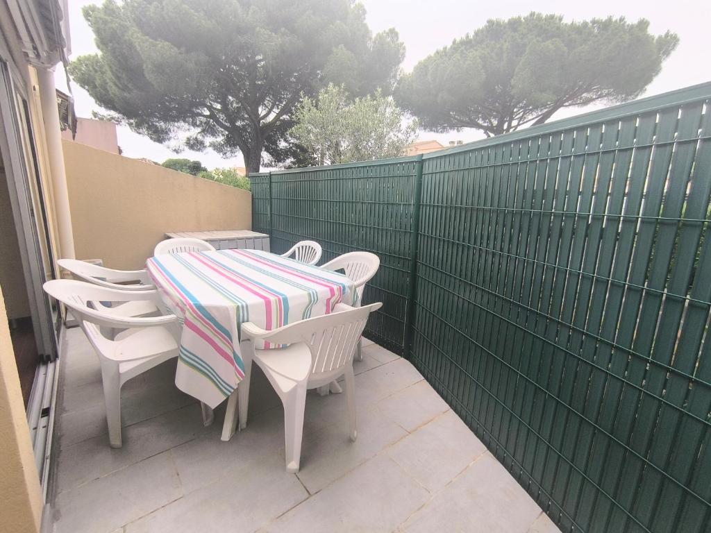 une table et des chaises sur une terrasse avec une clôture verte dans l'établissement 5070 Mas de la pinède 300, au Cap d'Agde