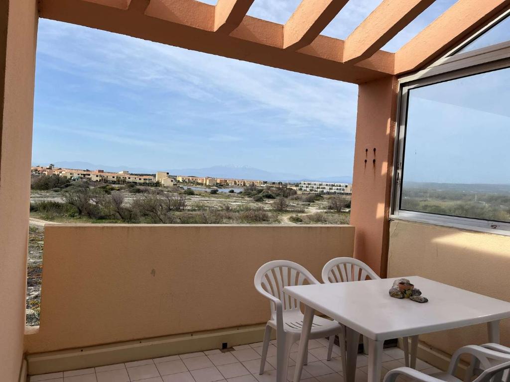 Appartement 2 pièces cabine 6 couchages PORT LEUCATE NATURISME PL080-TB21 في بورت لوكات: شرفة مع طاولة وكراسي ونافذة